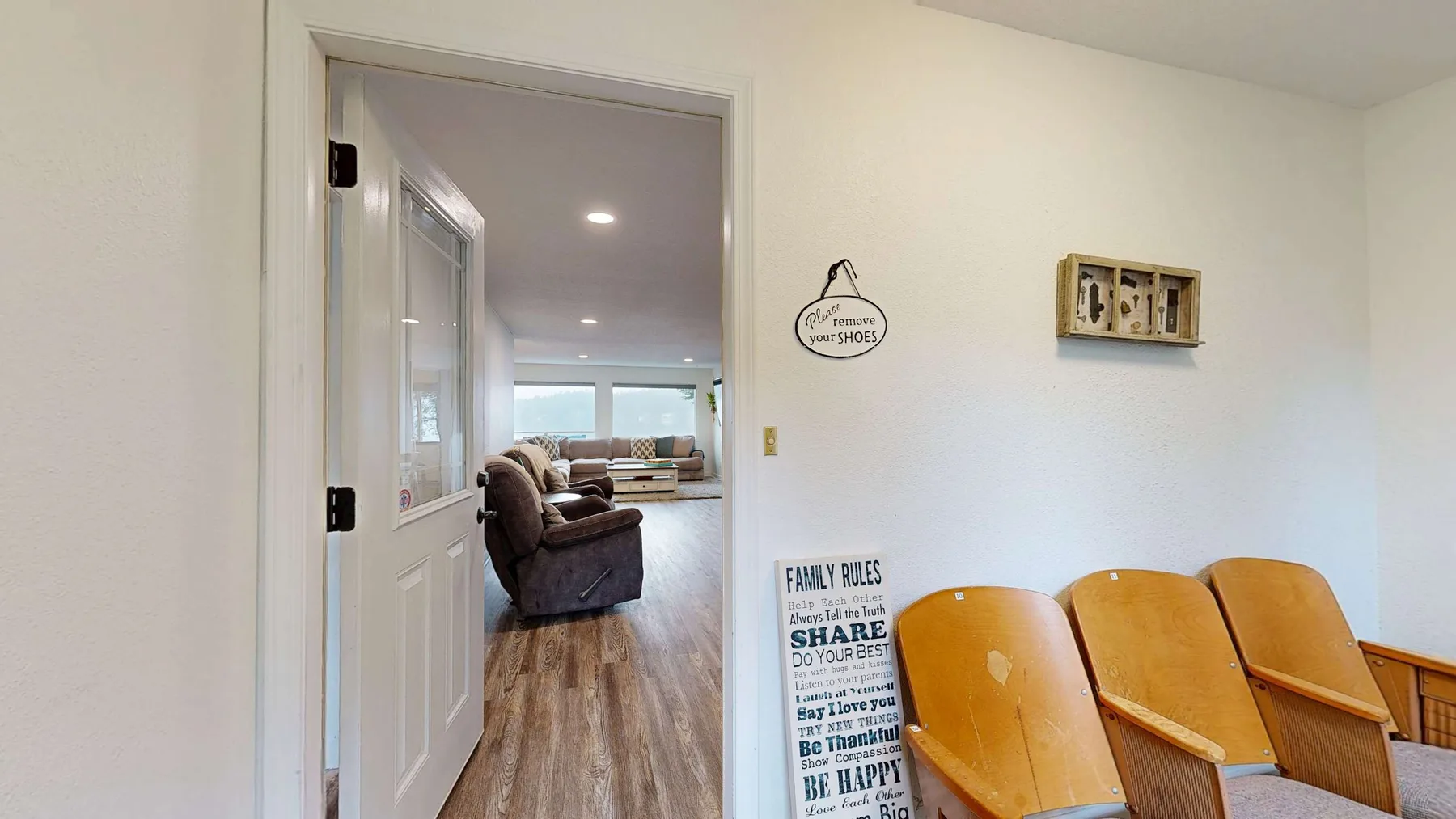 Una sala luminosa con suelo de madera y asientos visibles a través de la puerta.