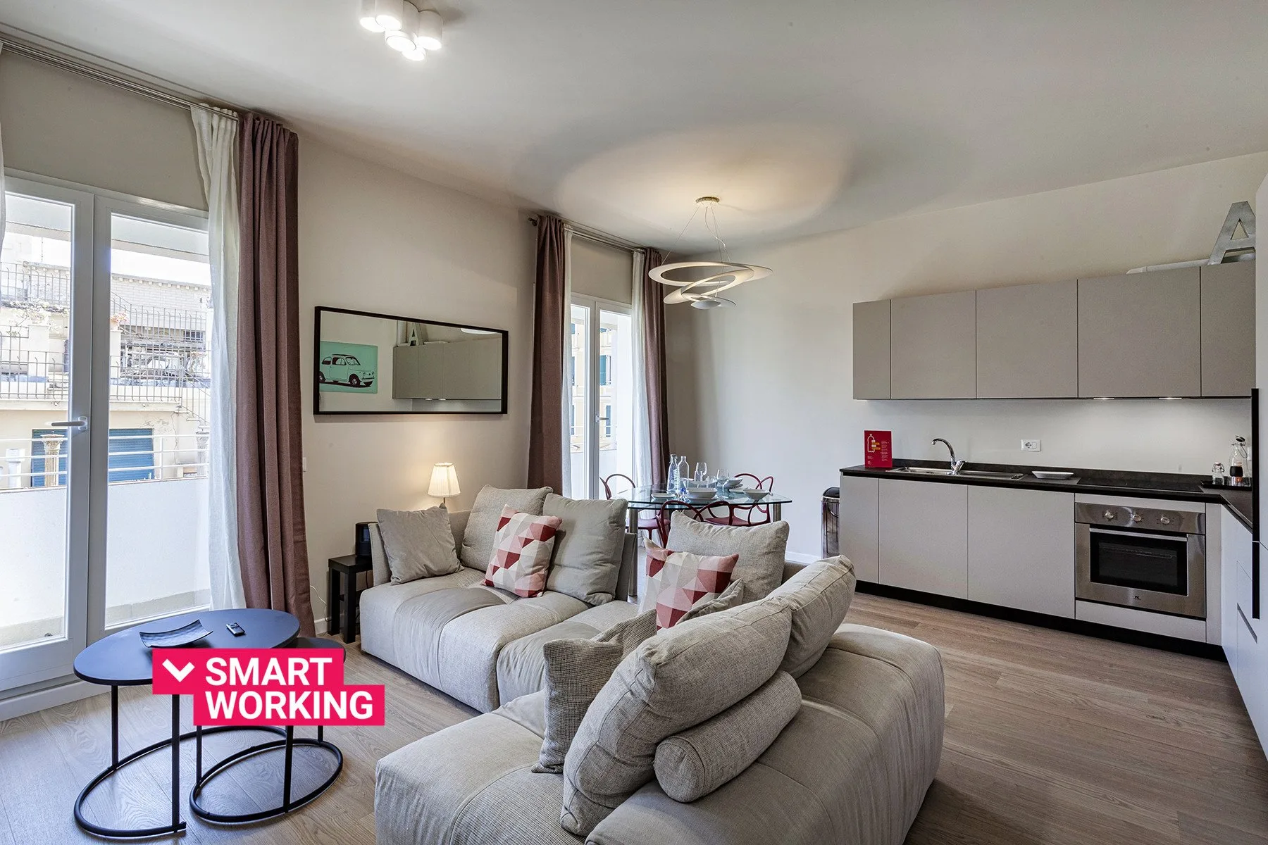 An open-plan living room and kitchen with seating beside a balcony door.