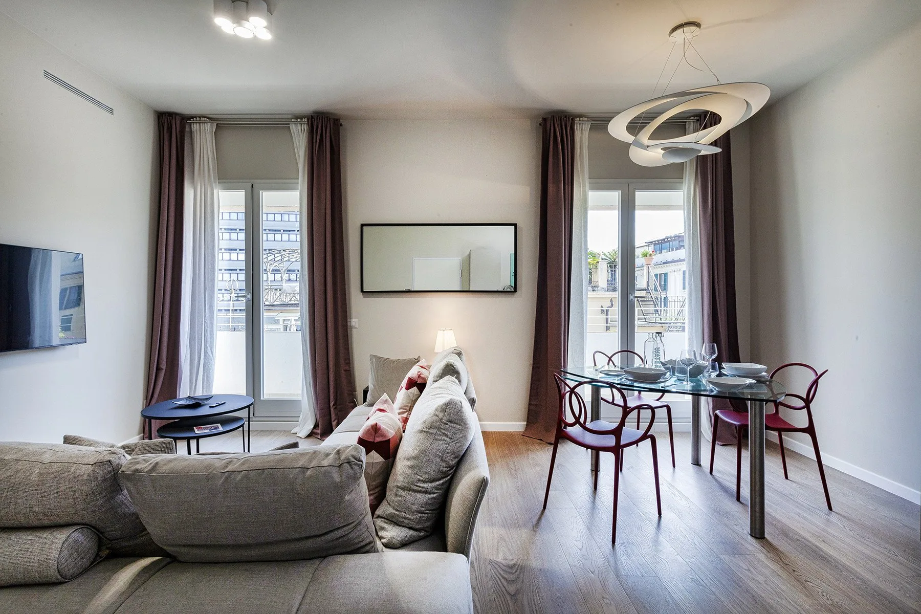 Una luminosa sala de estar y comedor con un sofá y una mesa junto a ventanas altas.