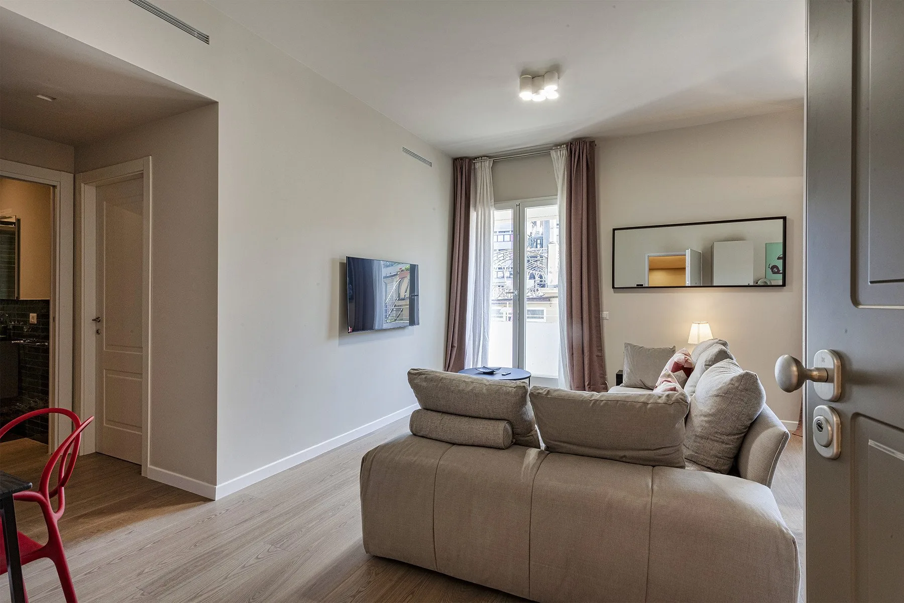 Una sala de estar con asientos, un televisor y una ventana alta.