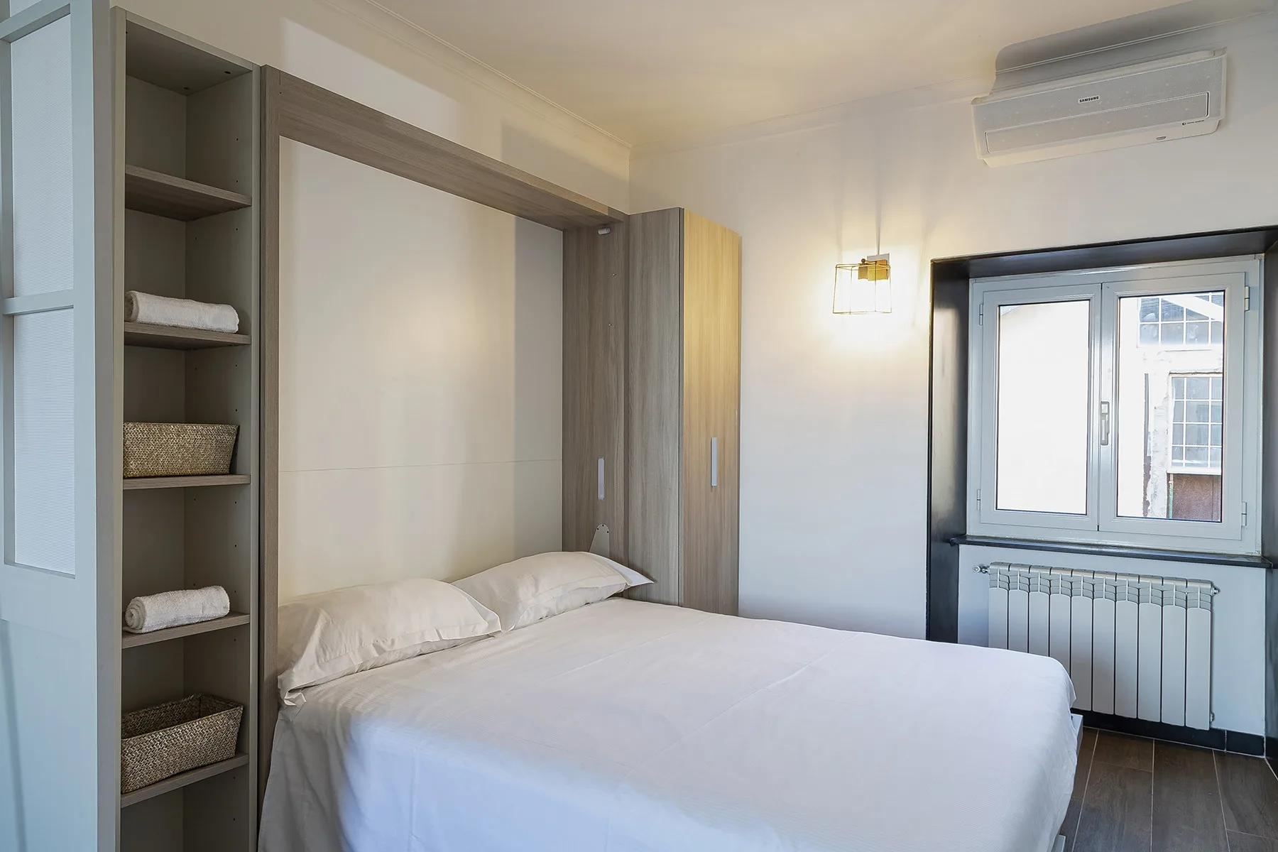 A bedroom with a neatly made bed beside a window.
