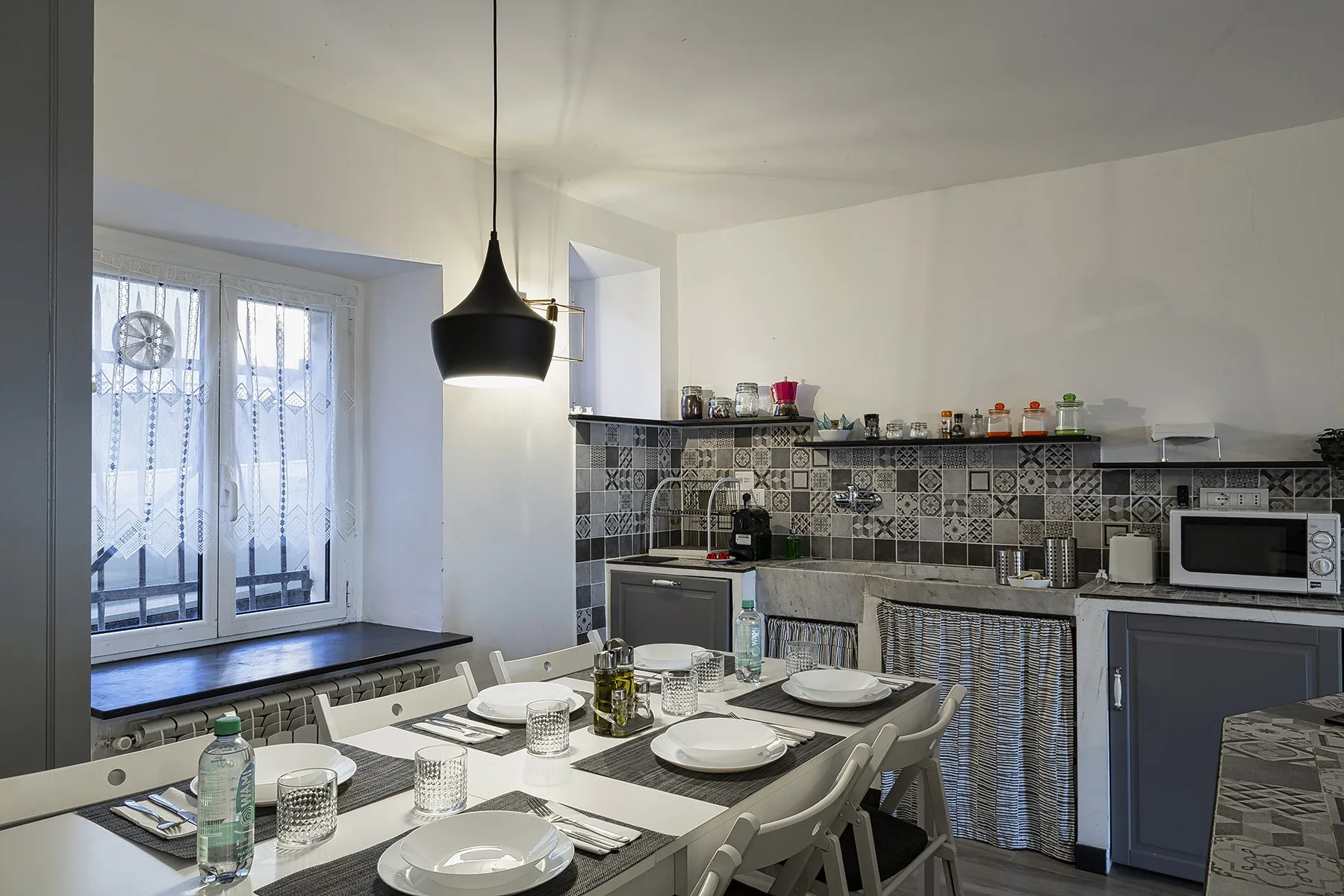 A bright kitchen and dining area with a table set beneath a pendant light.