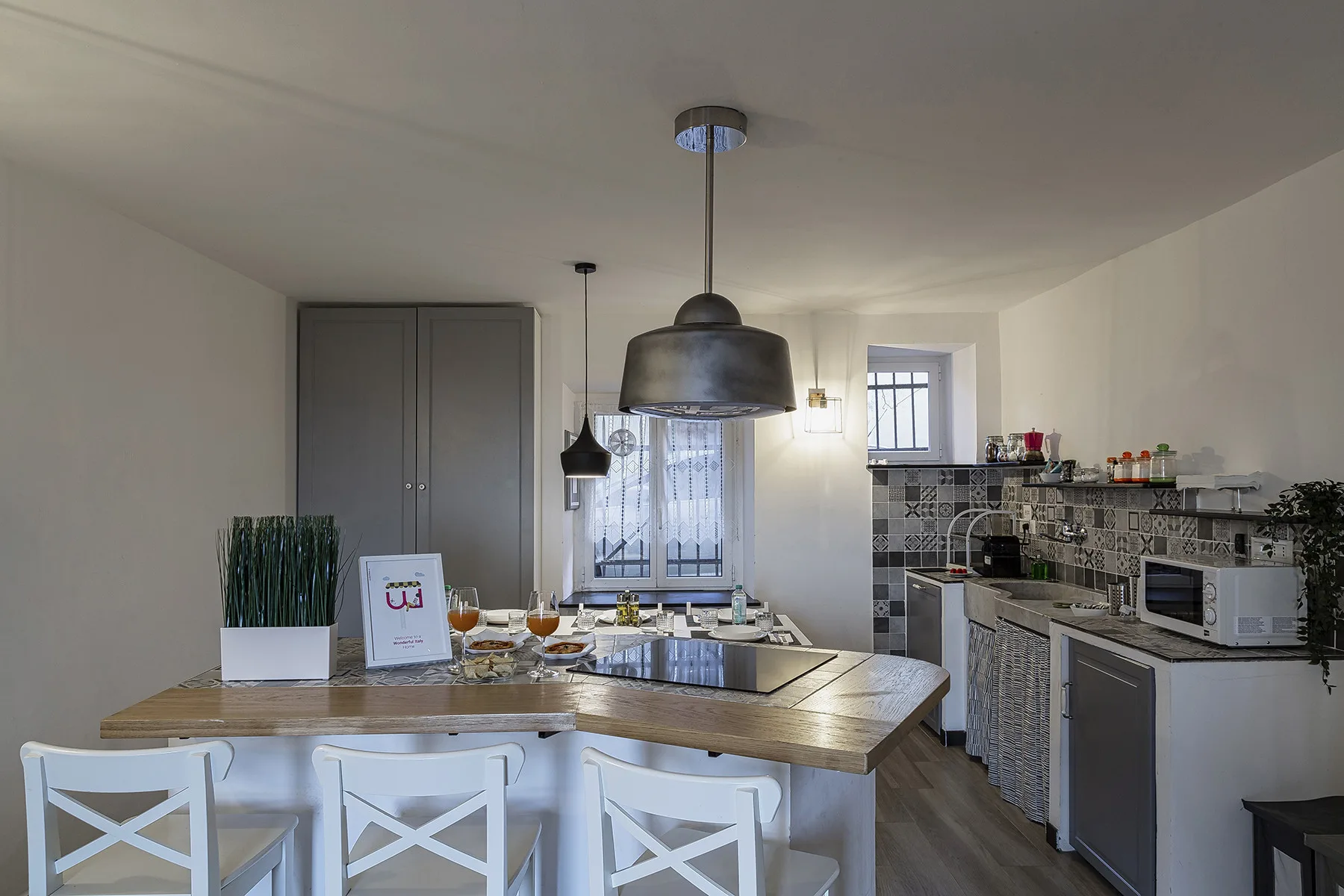 Una cocina luminosa con zona de comedor, isla de madera y asientos blancos.