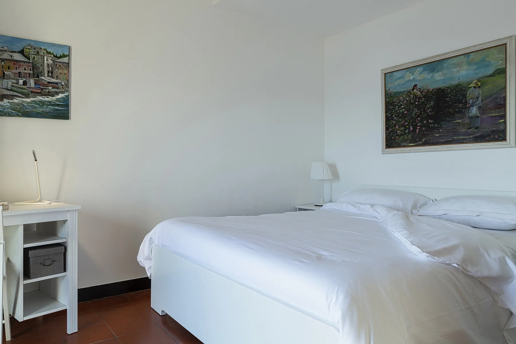 A bedroom with a neatly made bed and framed artwork on the walls.