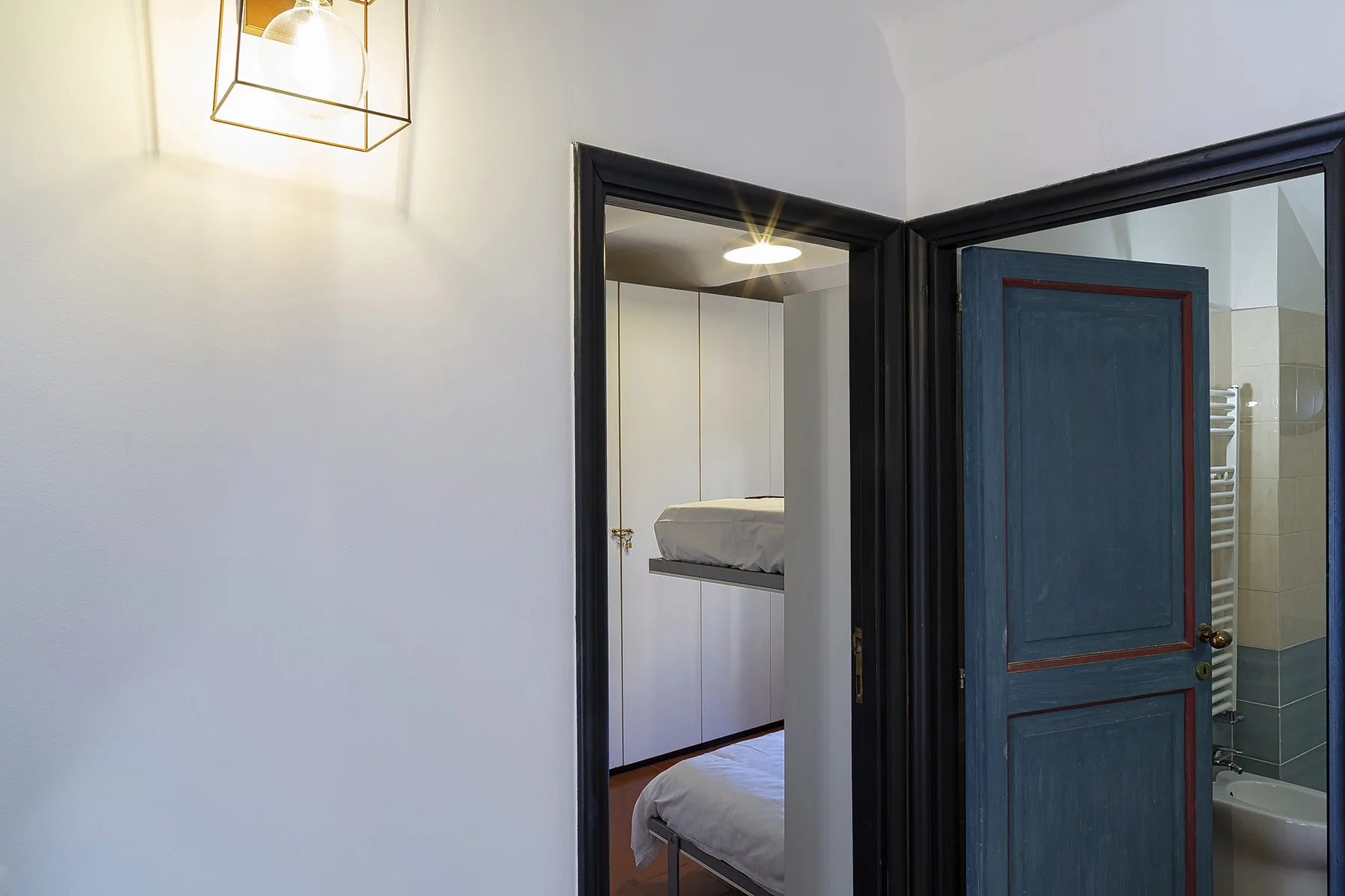 A bedroom is visible through a doorway beside an open bathroom door.