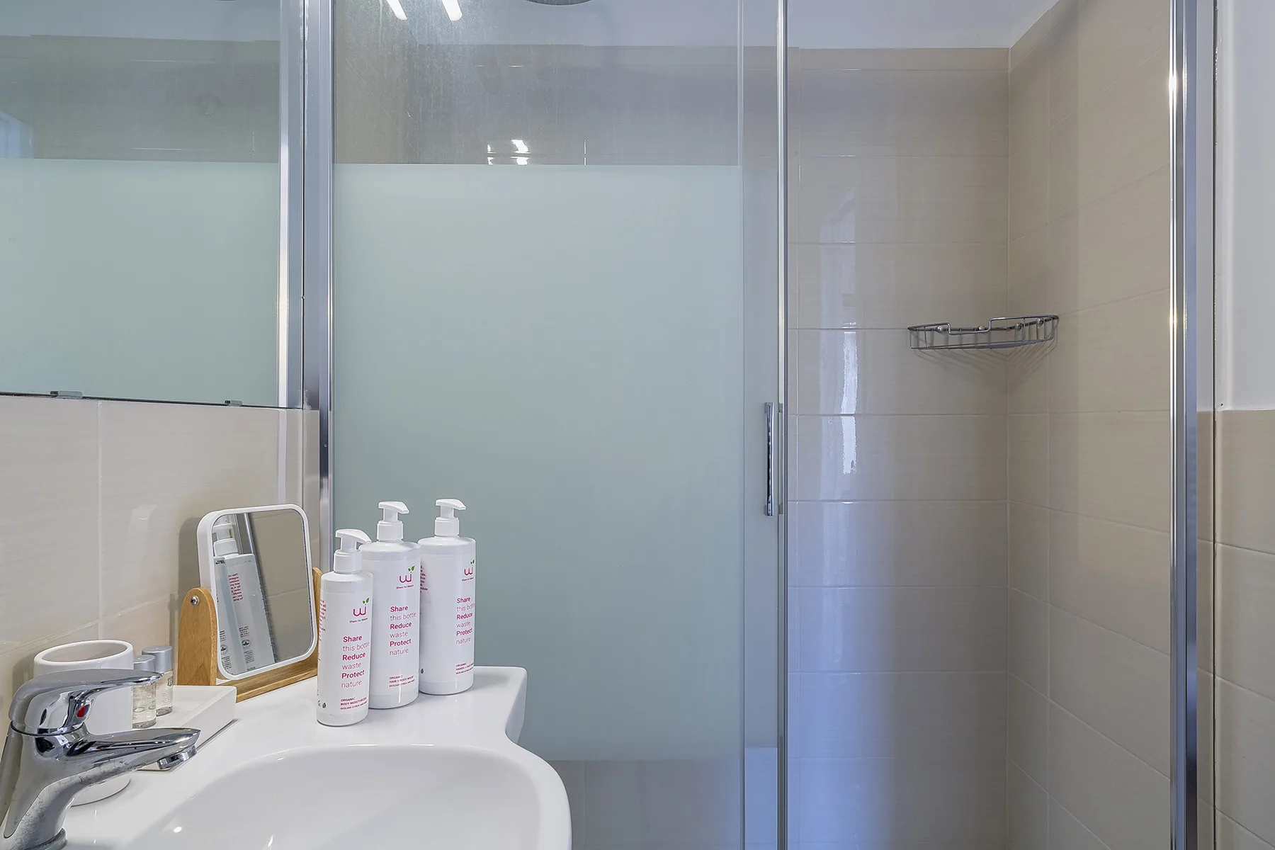 A bathroom with a frosted-glass shower and a sink.