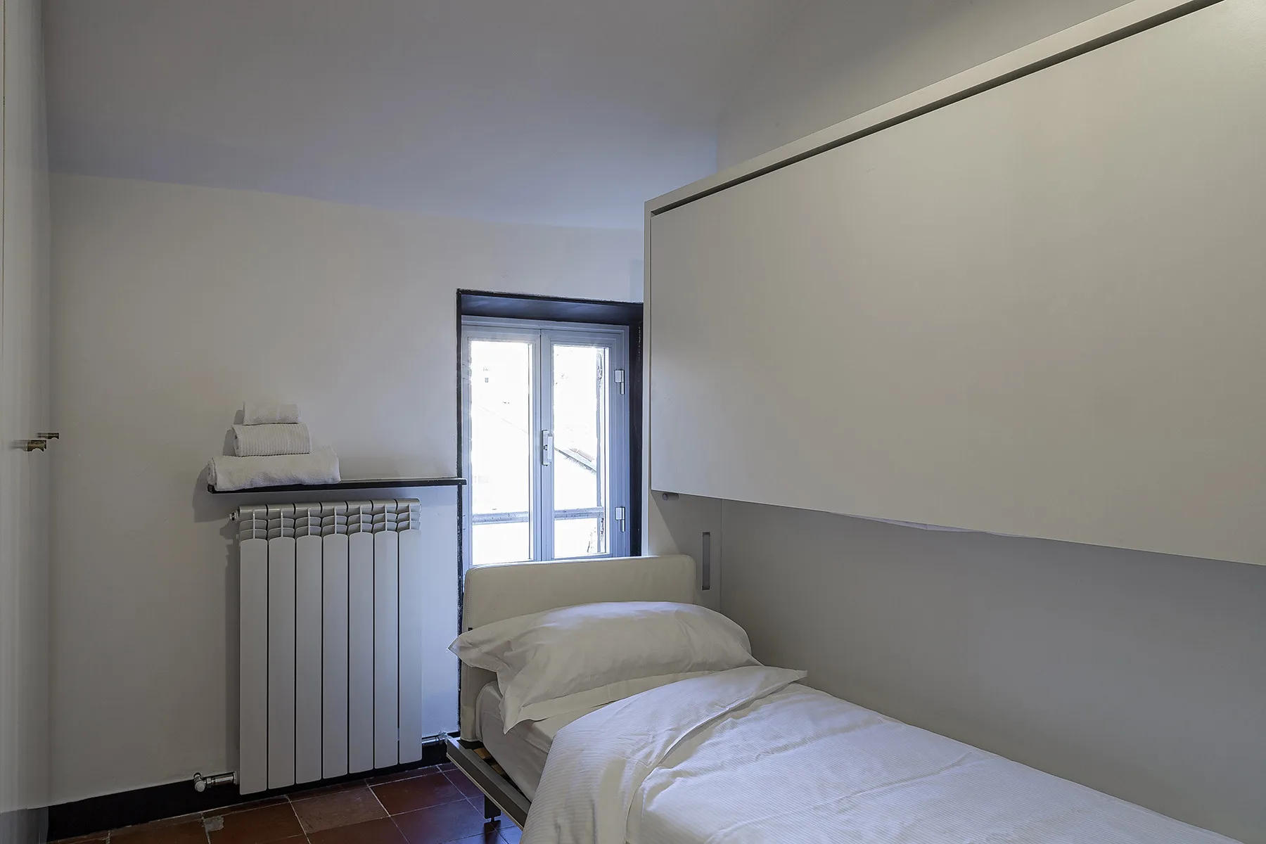 A bedroom with a single bed beside a window and radiator.