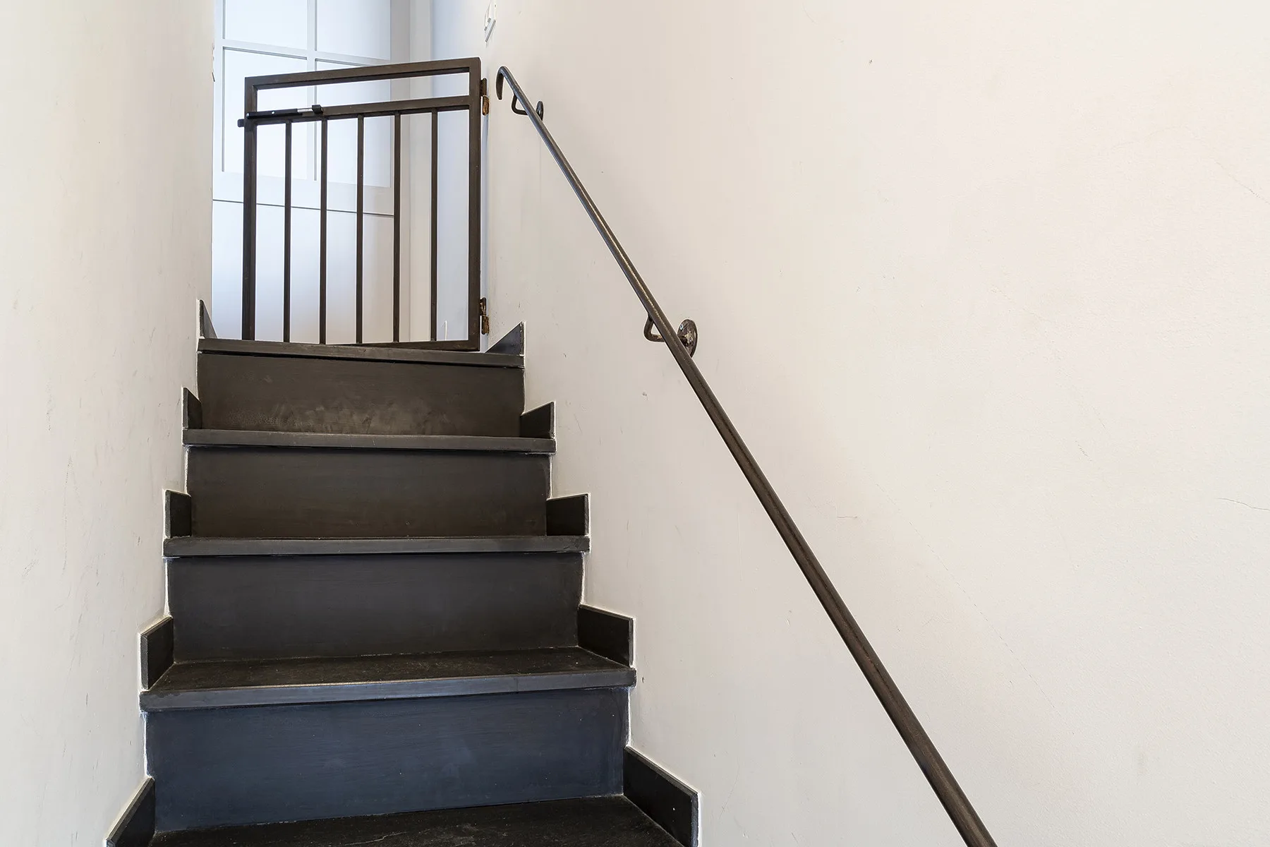 A staircase with dark steps and a handrail along the wall.