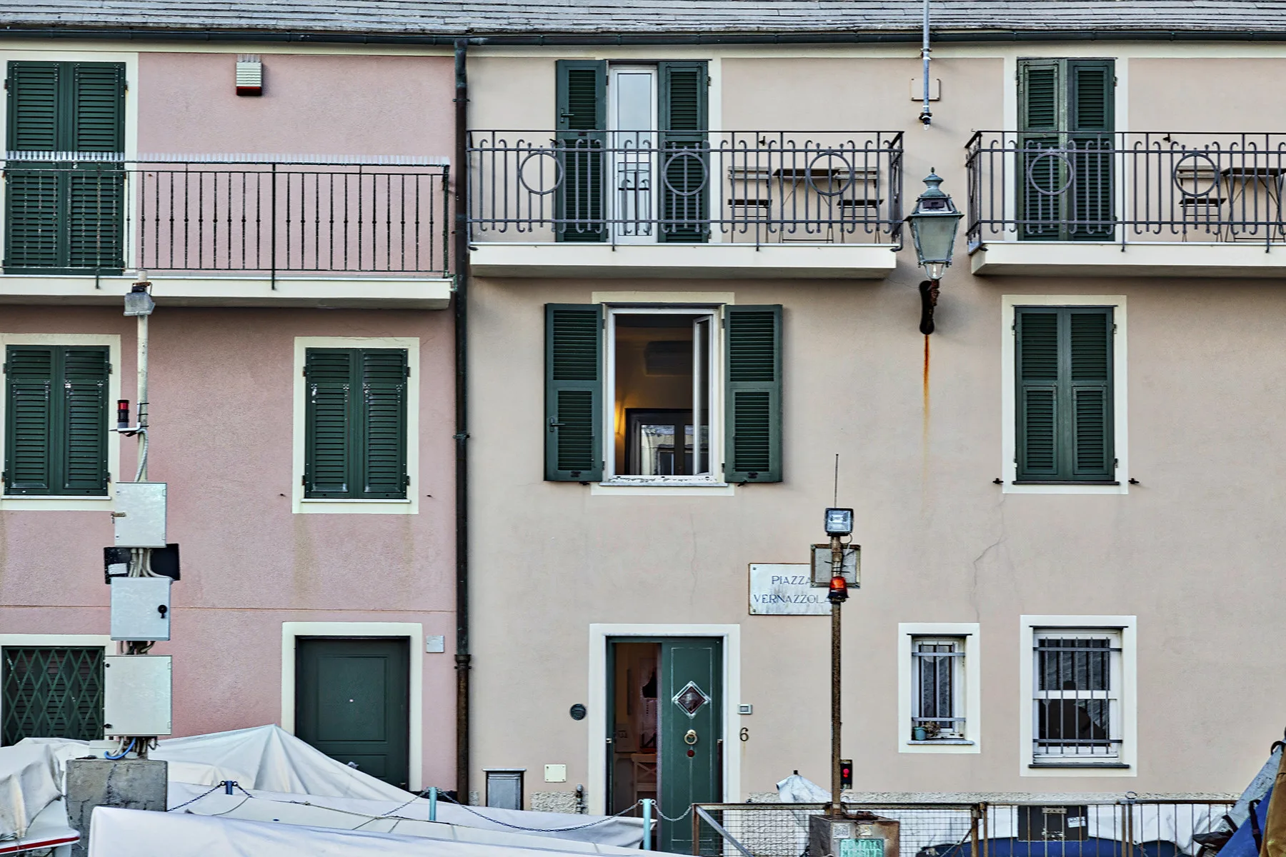 A pastel-colored building facade with shuttered windows and wrought-iron balconies.