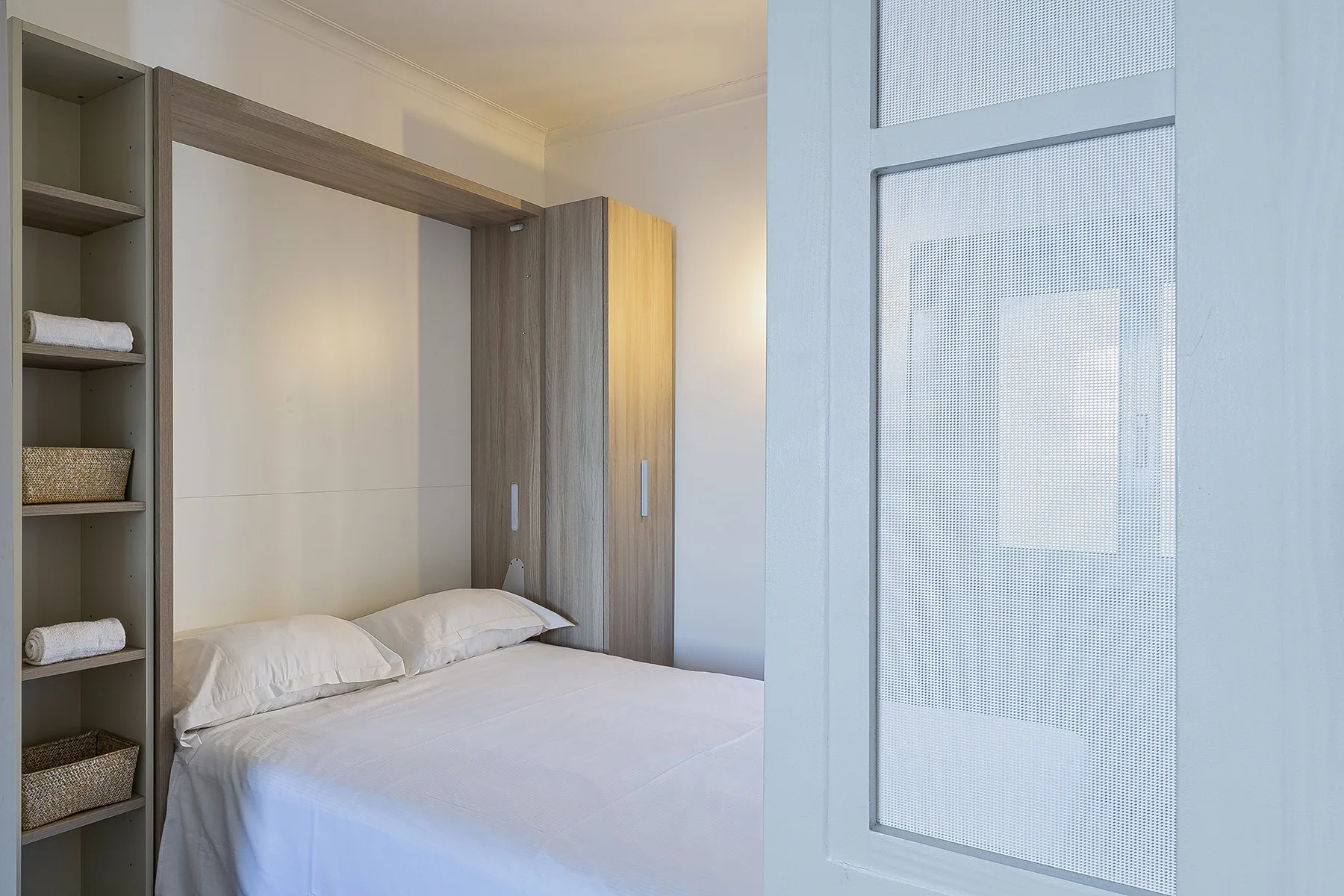 A bedroom with a neatly made bed and built-in shelving.