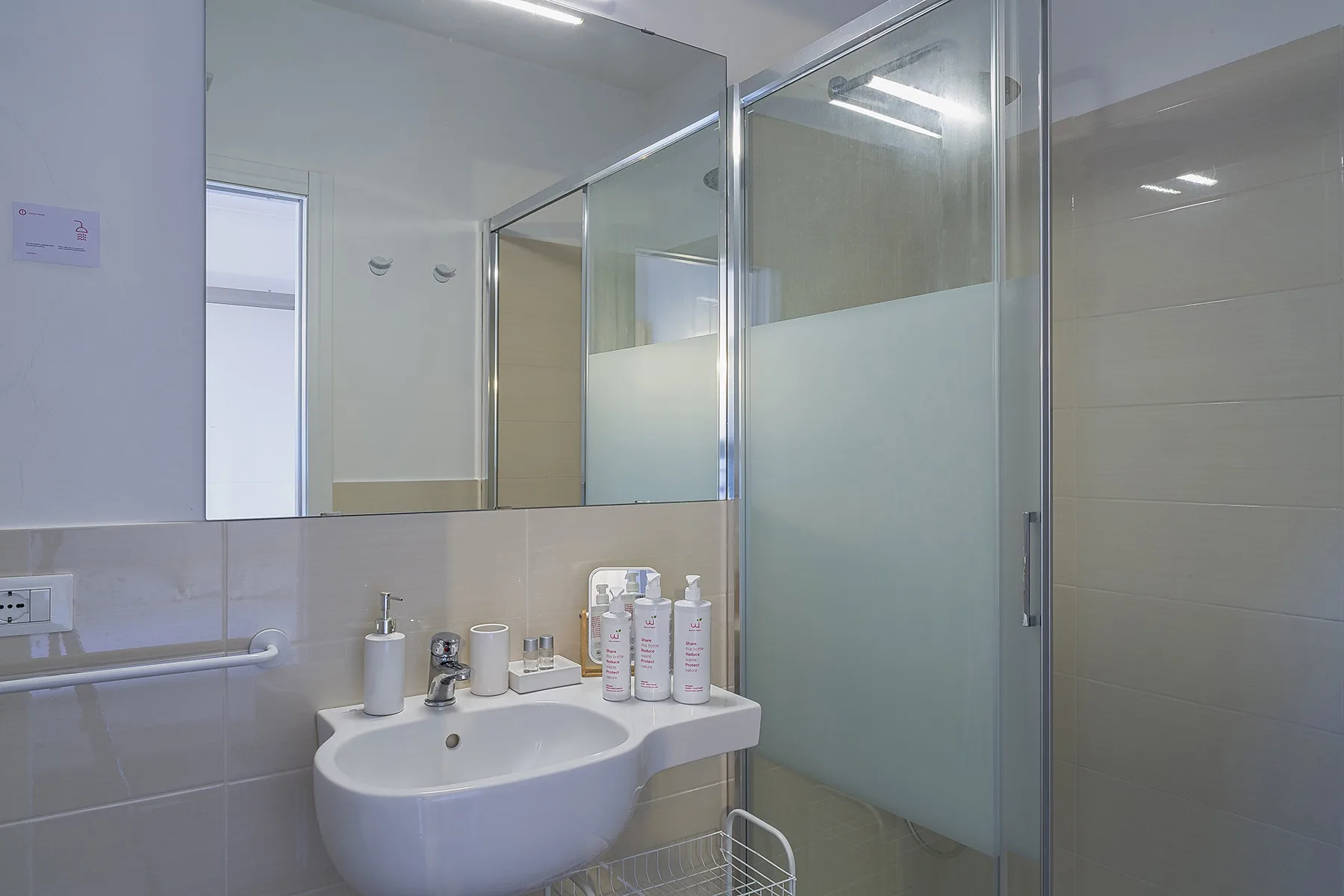 A tiled bathroom with a sink and a glass shower enclosure.