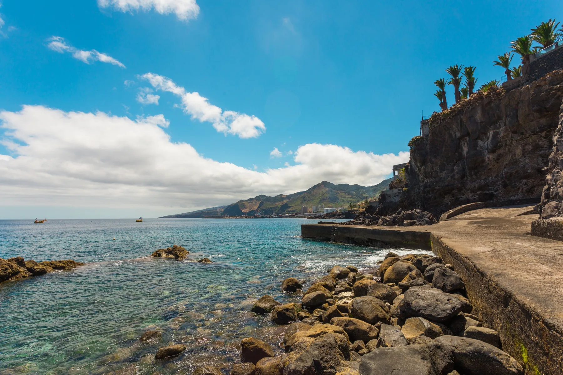 Una costa rocosa se encuentra con aguas claras junto a un paseo de piedra.