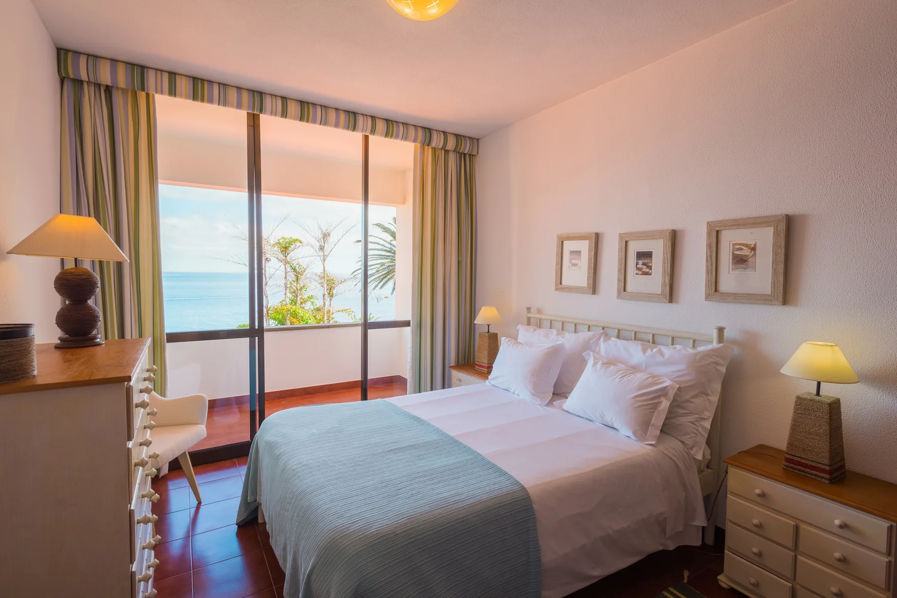 Un dormitorio con una cama tendida y puertas correderas de cristal con vistas al mar.