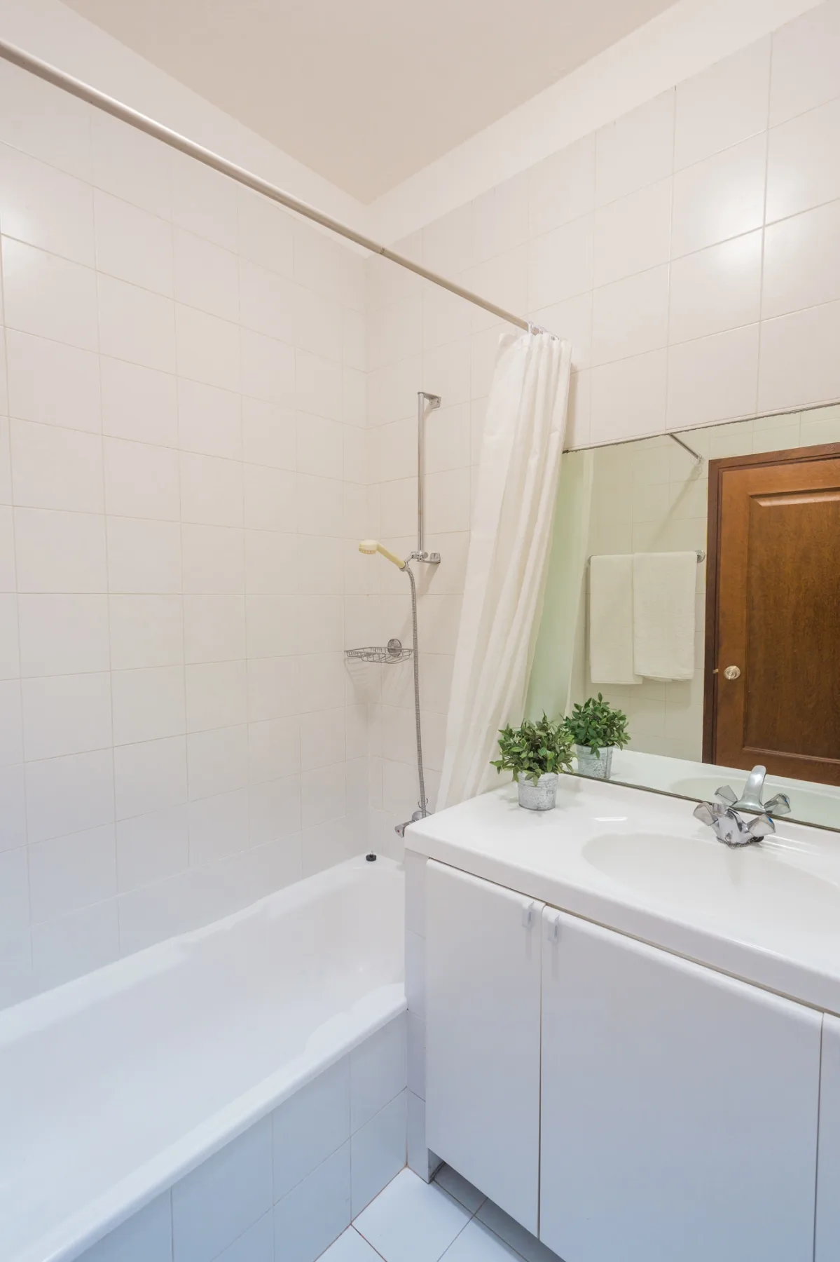 Un baño alicatado con bañera, ducha y lavabo.