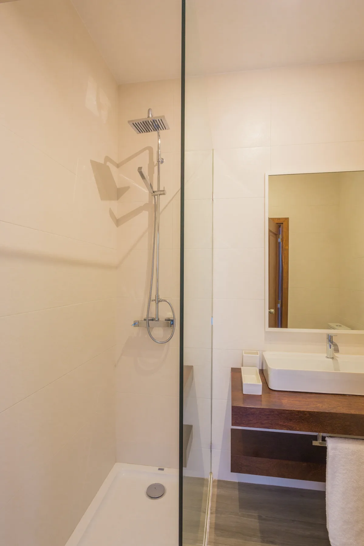Un baño con una ducha junto a un tocador y un espejo.