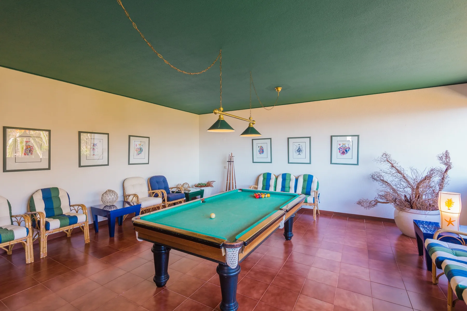 Una sala de juegos cuenta con una mesa de billar de paño verde y asientos.