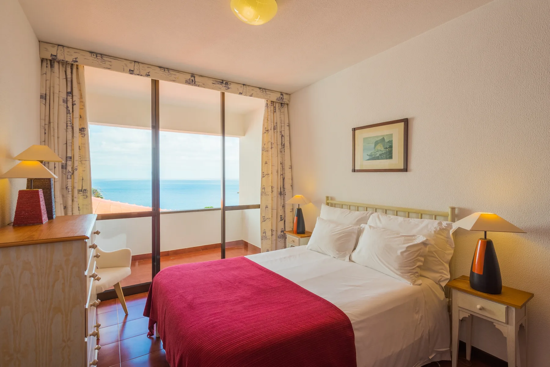 Dormitorio con una cama y grandes ventanas con vistas al mar.