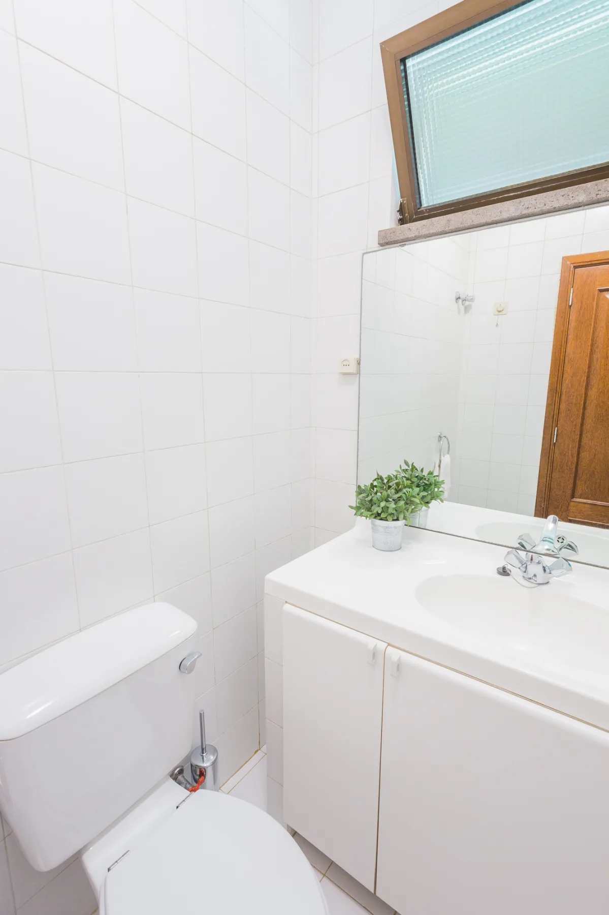 Un baño alicatado con un inodoro y un mueble blanco con lavabo.