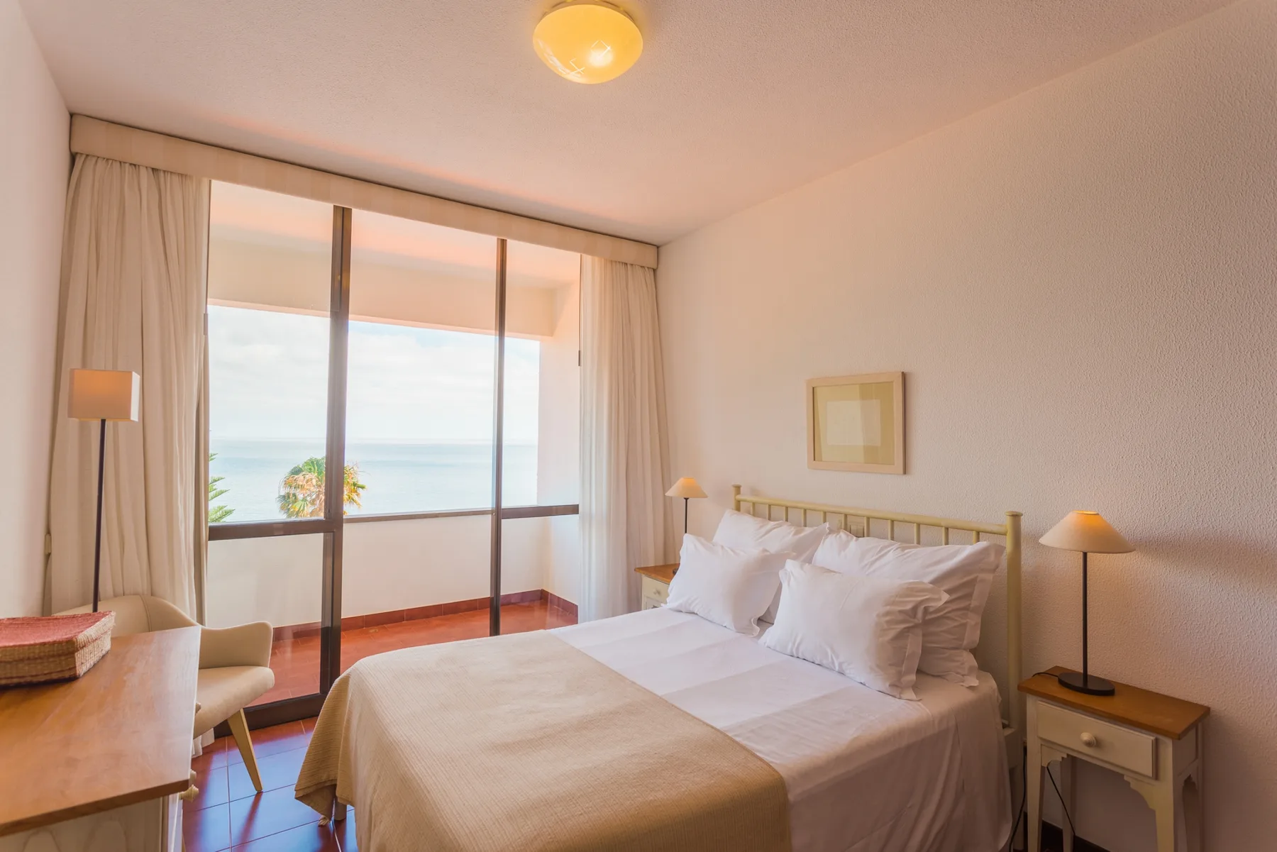 Un dormitorio con una cama doble y puertas correderas de cristal con vistas al mar.