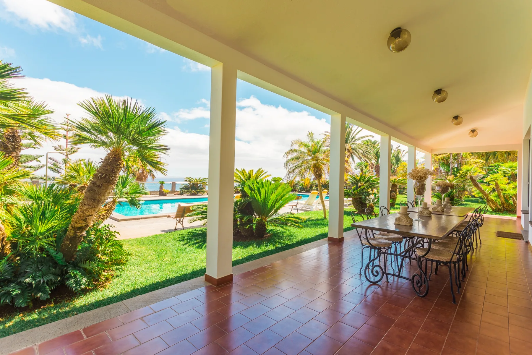 Comedor exterior cubierto con vistas a un jardín y una piscina.