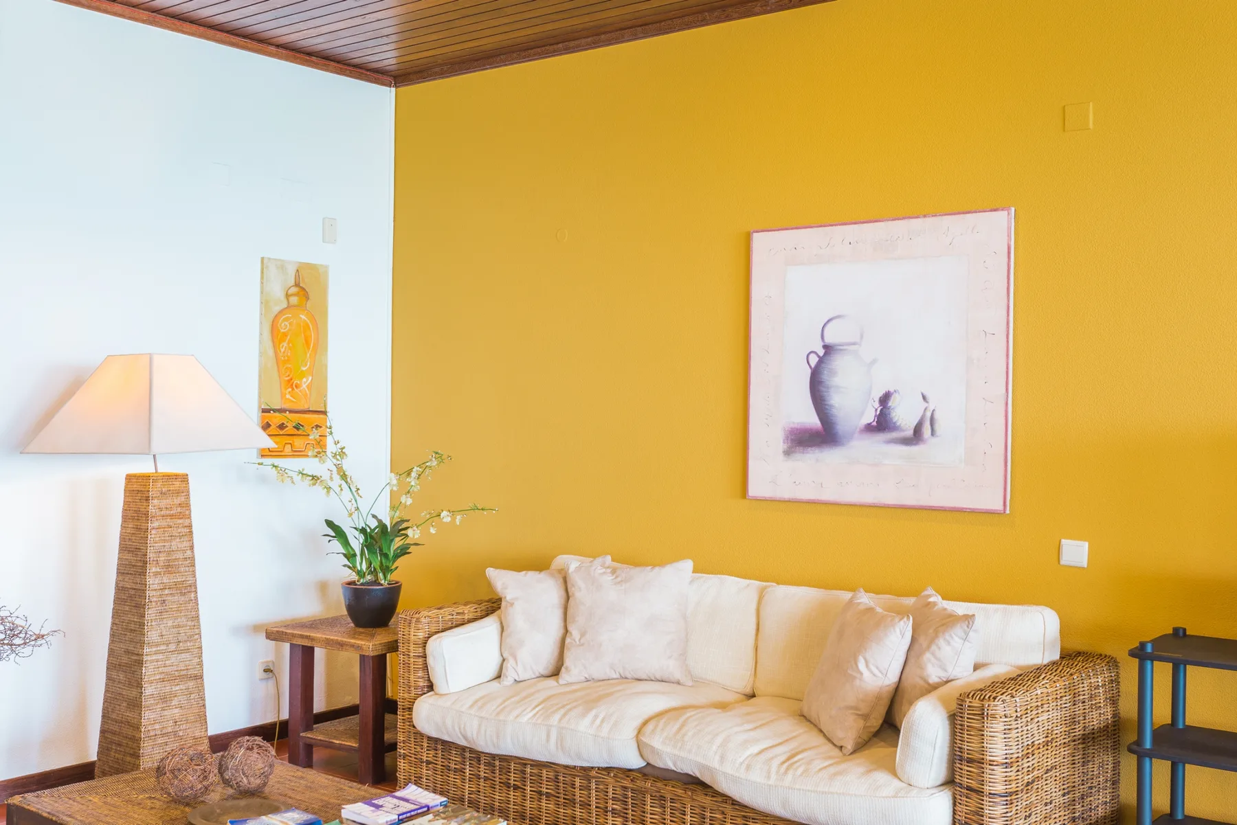 Sala de estar con asientos claros frente a una pared amarilla.