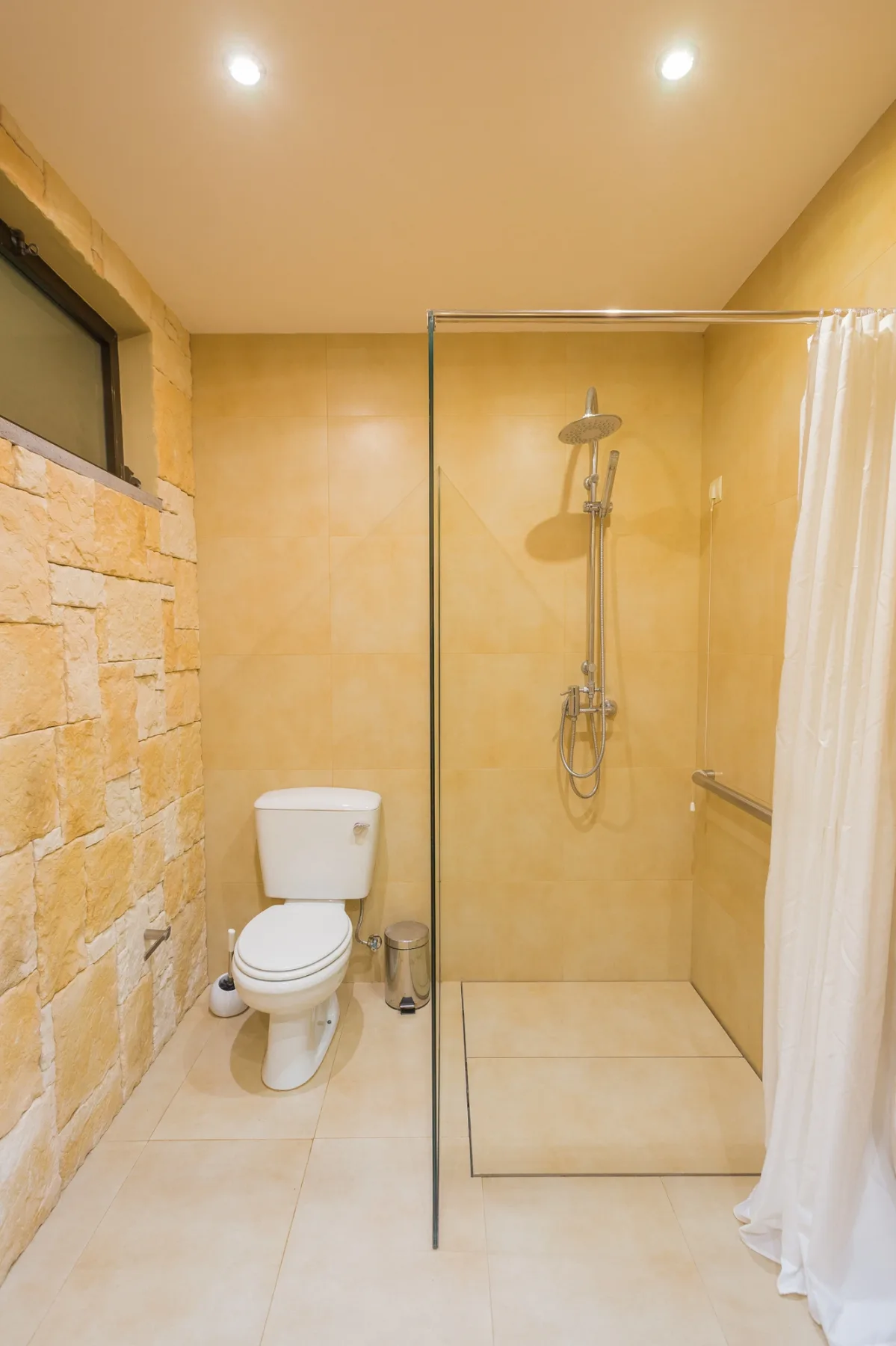 Un baño con un inodoro y una ducha con panel de vidrio.