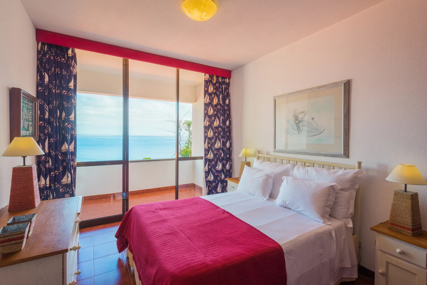 Un dormitorio con una cama frente a grandes ventanas con vistas al mar.