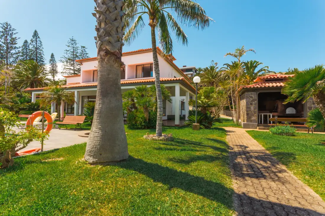 Una casa y una zona cubierta para sentarse están junto a un sendero del jardín.
