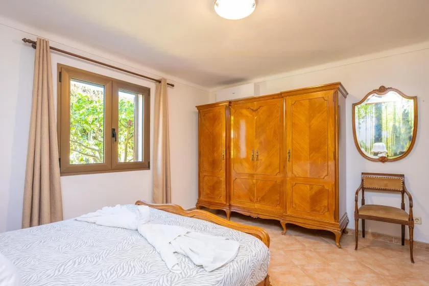 Un dormitorio con una cama, un armario grande de madera y una ventana.