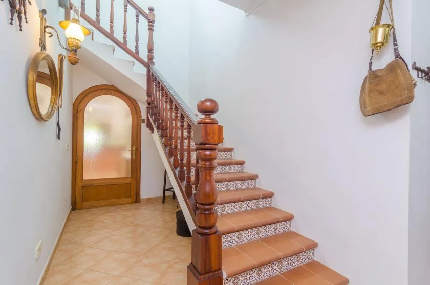 Una escalera interior con contrahuellas de azulejos decorados y una puerta de vidrio translúcido debajo.