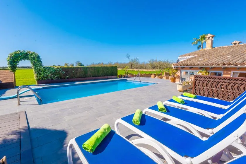 Una zona de piscina al aire libre con tumbonas azules junto al agua.