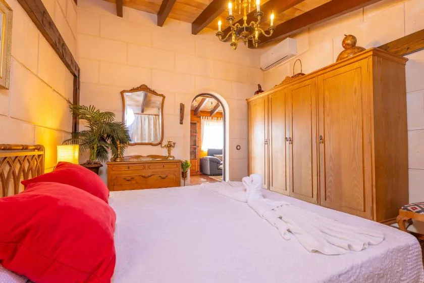 Un dormitorio con una cama grande, armarios de madera y vigas de techo a la vista.