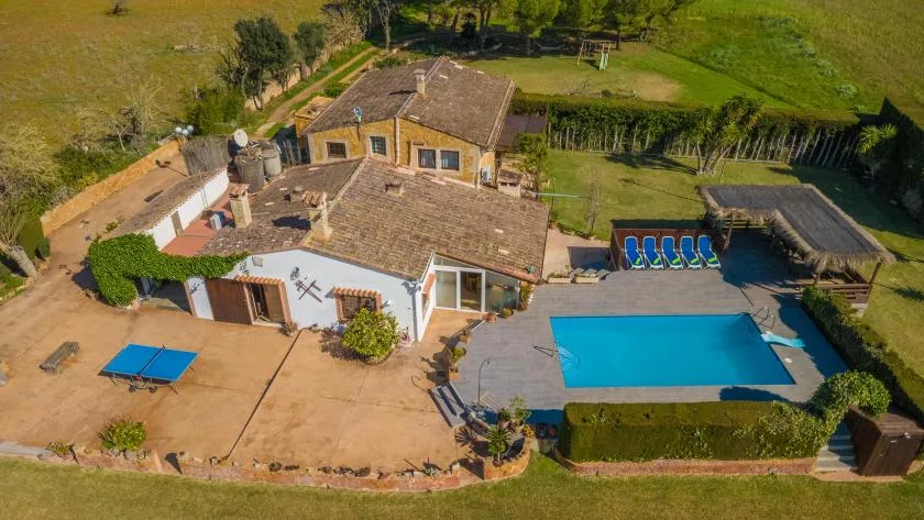 Vista aérea de una casa y una piscina al aire libre rodeadas de jardines.