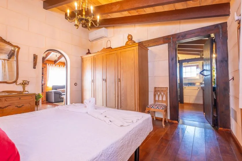 Un dormitorio con una cama, un armario de madera y una puerta abierta.