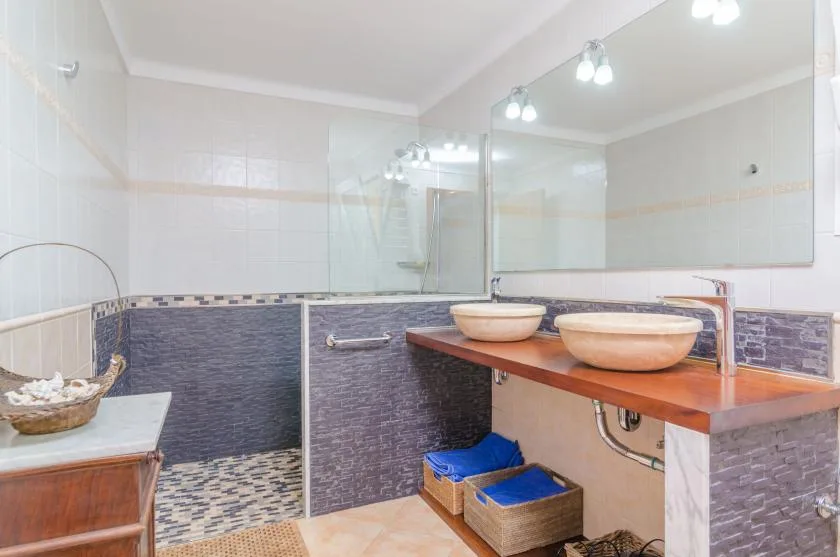 Un baño alicatado con ducha y un tocador con dos lavabos.