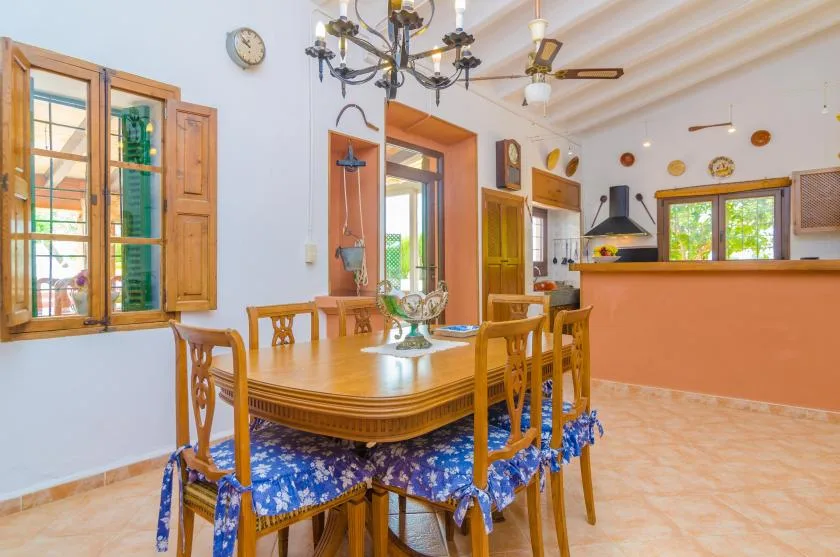 Un comedor con una mesa de madera y sillas junto a ventanas abiertas.