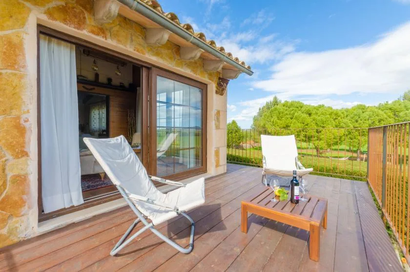 Una terraza de madera con asientos reclinables da a un paisaje verde.