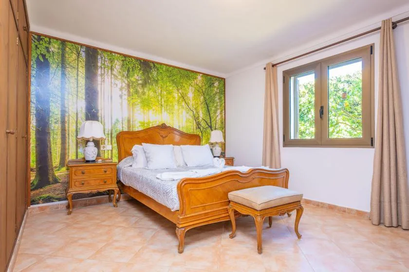 Un dormitorio con una cama de madera y un mural de bosque detrás.