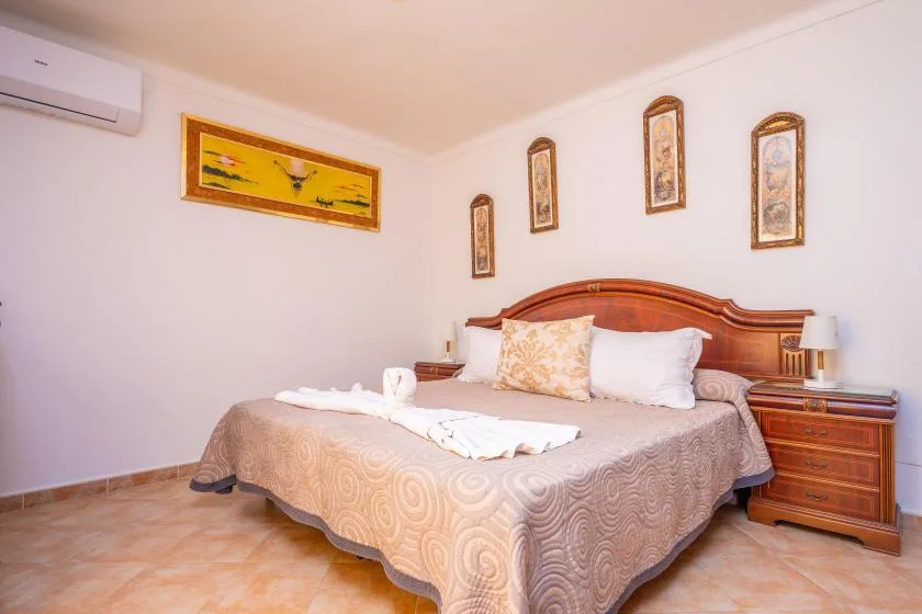 Un dormitorio con una cama doble, cabecero de madera y cuadros en la pared.