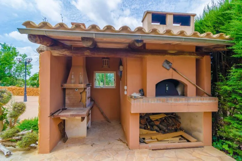 Una zona de cocina al aire libre con un horno integrado y un espacio para guardar leña.