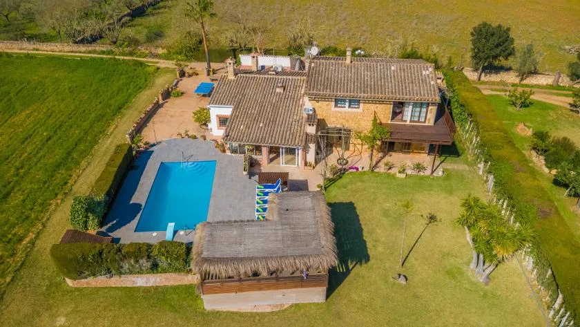 Una vista aérea muestra una casa, una piscina y un amplio jardín con césped.