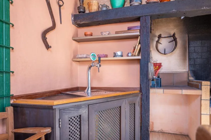 Una barra rústica con un grifo metálico y estantes con cerámica.