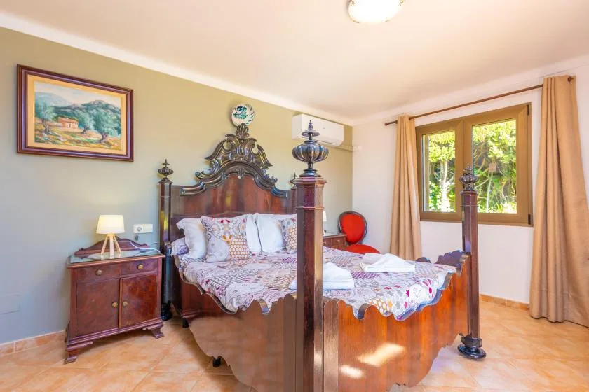 Un dormitorio con una cama con dosel de madera y una ventana con cortinas.