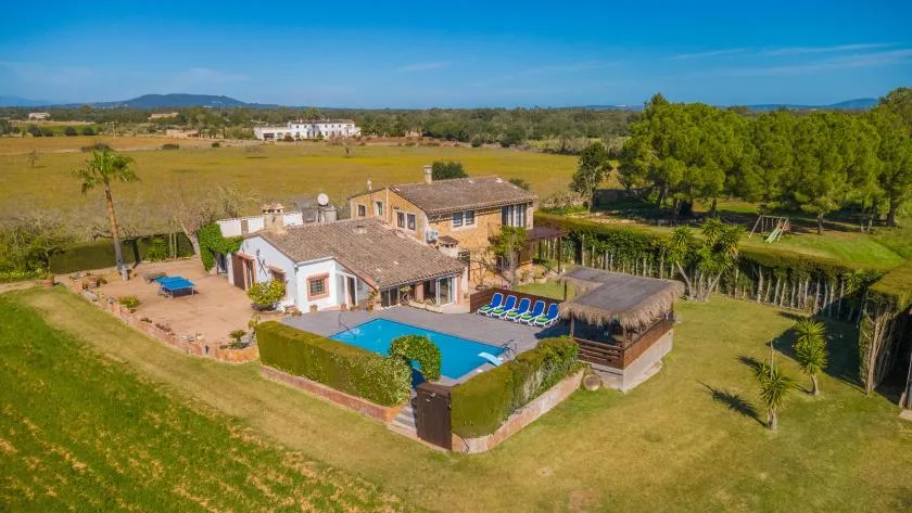 A countryside property with a swimming pool, patio, and surrounding fields.