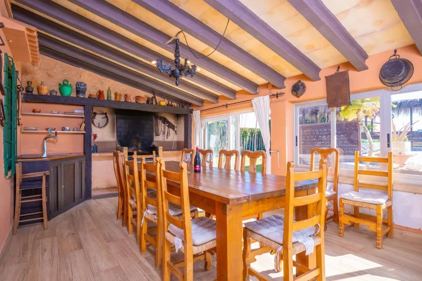 Un comedor con una mesa larga de madera y sillas bajo vigas expuestas en el techo.