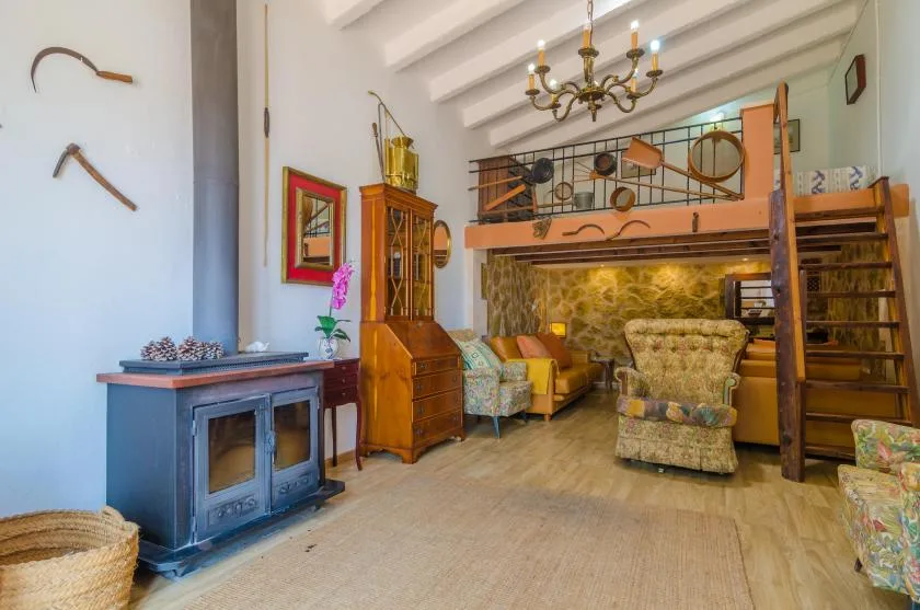 Una sala de estar con asientos bajo un altillo elevado y una escalera de madera.