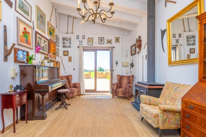 Una sala de estar luminosa con un piano y asientos junto a puertas de vidrio.
