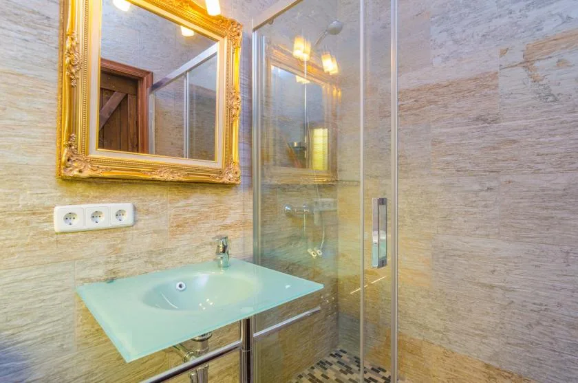 Un baño alicatado con ducha de vidrio y lavabo suspendido.