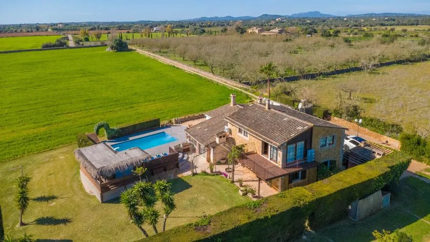 Una casa y una piscina están junto a campos verdes en un paisaje rural.