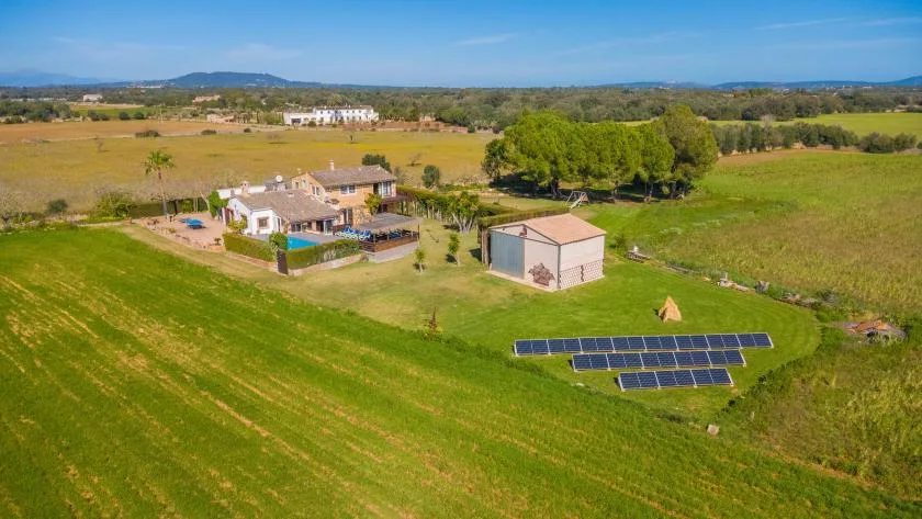 Vista aérea de una propiedad rural con paneles solares en un campo verde.